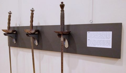 Dueling swords hanging on fencing sword wall mount